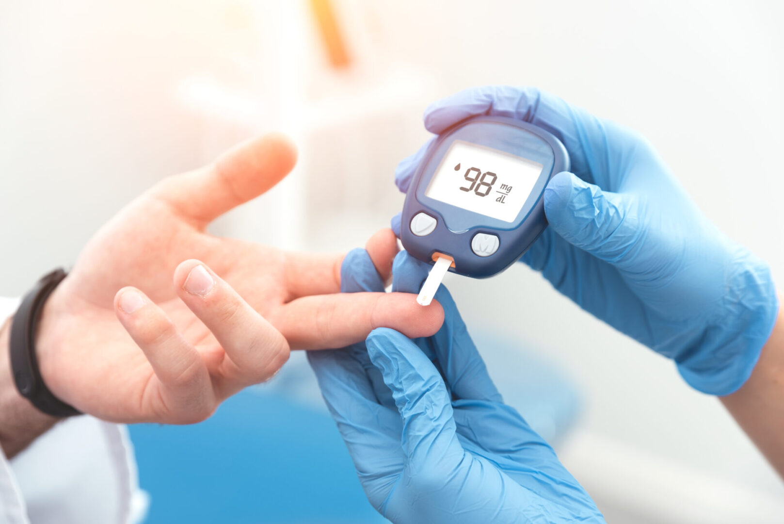 A healthcare professional uses a glucometer on a patient's fingertip to measure blood sugar levels.